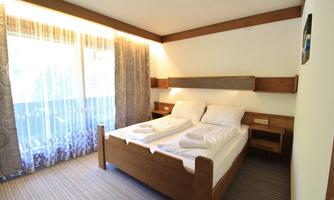 A cozy bedroom with a double bed and fresh towels.  
Large windows provide plenty of daylight and a pleasant view.
