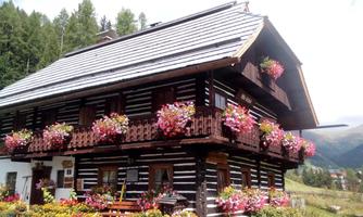 A traditional wooden house with beautiful flower boxes and balconies. The surroundings are green and picturesque.