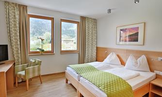 A bright and modern hotel room with two beds and large windows. View of nature and simple, stylish furniture.