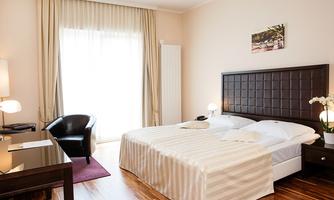 A modern bedroom with a double bed and a desk. Large windows provide plenty of natural light and a cozy atmosphere.