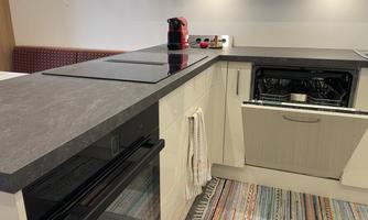 A modern kitchen with a gray workspace. In the foreground, a dishwasher and a stove are visible.