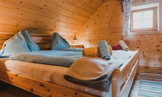 A cozy bedroom with wood paneling and a large bed. On the bed are some pillows and towels.
