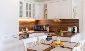 Modern kitchen with white cabinets and a wooden countertop. An inviting dining area with a table and chairs is also present.