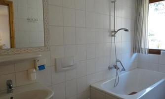A modern bathroom with a bathtub and a shower. There is a mirror and a window that lets in natural light.