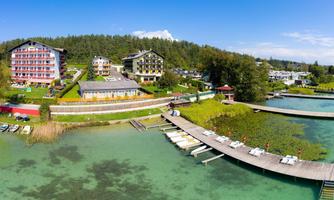 A picturesque landscape with several hotels by the water. The clear pond and wooden walkways create an inviting atmosphere.