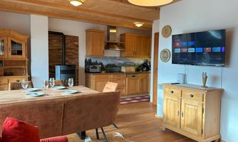A cozy kitchen-living room with wooden furniture and modern amenities. The space is bright and inviting, perfect for relaxed evenings.