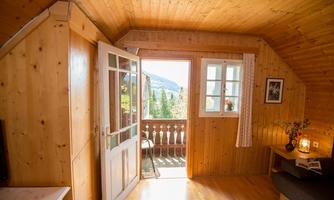 A cozy room with wooden walls and a balcony. The view outside reveals a beautiful natural scenery.