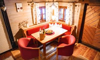 A cozy dining area with a wooden table and red chairs. The light shines through the windows, creating an inviting atmosphere.