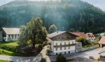 A picturesque inn amidst green hills and forests. The surroundings are calm and inviting, perfect for a getaway in nature.