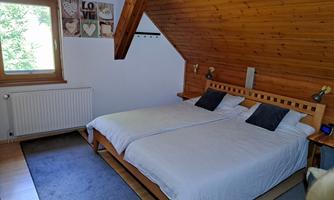A cozy bedroom with two single beds. Decorative pictures hang on the wall, and a window allows for natural light.