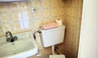 A small bathroom with a toilet and a sink. The walls are decorated with a light, flower-like pattern.