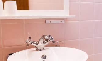 A modern sink in a stylish bathroom. The walls are in soft shades of pink and there is a large mirror.