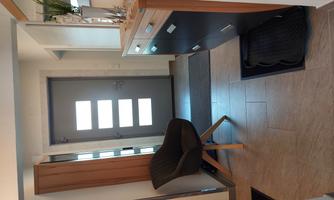 A bright hallway with a gray door and modern furniture. A comfortable chair and a shoe cabinet are clearly visible.