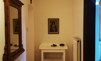 A bright hallway with a mirror on the wall and a small table. A picture is hanging on the wall, and the floors are made of wood.