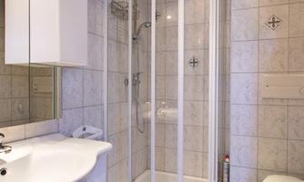 A modern bathroom with a shower enclosure, a sink, and a toilet. The walls are styled with bright tiles.