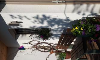 Inviting entrance area with a wooden bench and colorful flowers. Decorative elements and plants are hanging on the wall.