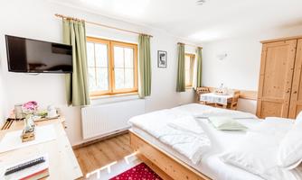 A bright bedroom with a large bed and a cozy decor. There is a window with a view outside and a television on the wall.