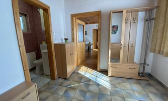 A bright hallway with wooden paneling and linoleum flooring. In the background, doors to other rooms are visible.