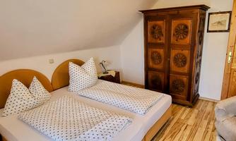 A cozy bedroom with two single beds and traditional furniture. The room has wooden flooring and a warm atmosphere.