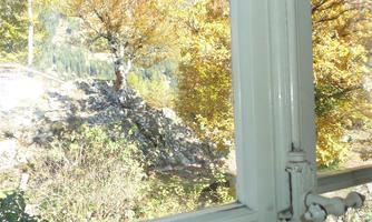 A view from a window onto an autumn landscape. Trees with golden leaves and rocky vistas surround the scene.