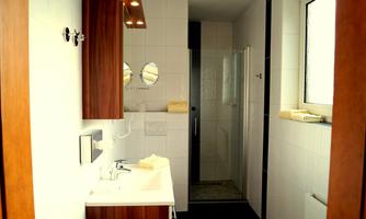 A modern bathroom with a shower and a sink. Bright tiles and wooden elements create an appealing atmosphere.