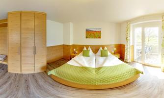 A cozy bedroom with a large, double occupancy bed and a green bedspread. Bright walls and large windows create a friendly atmosphere.