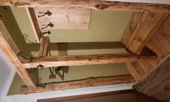 A cozy entrance area with a wooden coat rack and hooks. The walls are painted in a soft green tone.