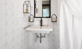 A modern bathroom with bright tiles and an elegant sink. Stylish lighting and decorative elements hang on the wall.