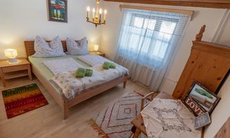 A cozy bedroom with a double bed and soft colors. The room is bright and inviting, with a lovely window view and decorative rugs.