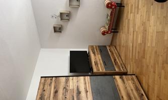 A modern room with a wooden cabinet and a television. There are also some shelves on the wall and a red armchair.