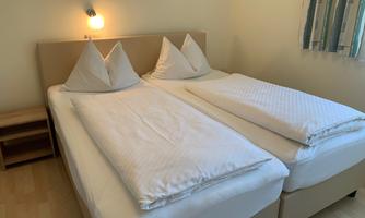A cozy room with two separate beds and white bedding. The room lighting creates an inviting atmosphere.