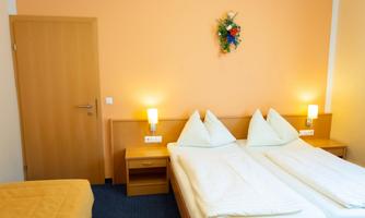 A simple hotel room with two single beds and a striking wall decoration. The walls are orange and there is a cozy atmosphere.