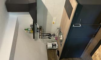 A modern kitchen with a wooden workspace and a stove. There is also a coffee machine and some kitchen utensils.