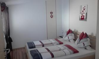 A cozy bedroom with two beds and decorative pillows. The walls are in neutral colors, enhanced by romantic decorations.
