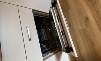 A modern kitchen with a built-in dishwasher. The dishwasher is slightly open and shows the interior.