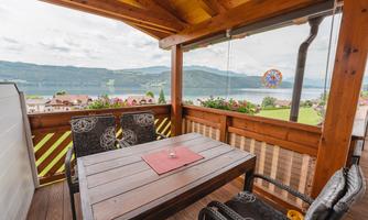 A balcony with wooden furniture and a view of a lake and the mountains. The cozy atmosphere invites you to relax.