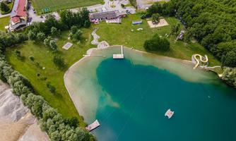 A beautiful lake with clear water and green shores. In the background, there are recreational areas and a water feature.