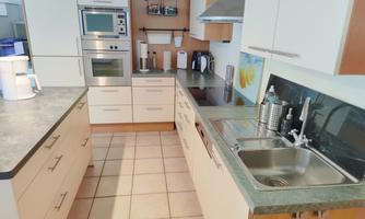 A modern kitchen with bright furniture and stainless steel appliances. The room is well organized and offers plenty of storage space.