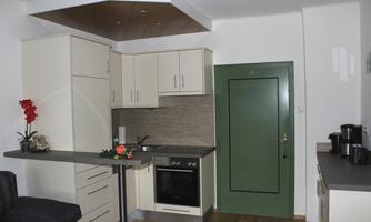 A modern kitchen with bright cabinets and an elegant countertop. In the background, there is a green door and some kitchen appliances visible.