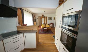 Modern kitchen with wooden surfaces and high-quality appliances. View of the adjacent living area with a cozy dining space.