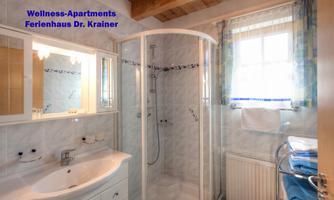 A modern bathroom with a shower, sink, and large mirrors. Towels and toiletries are neatly arranged.