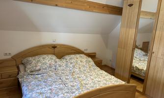 Bedroom with a double bed and wooden furniture. The room has a large mirror and a cozy atmosphere.