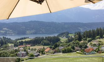 A picturesque landscape with hills, a clear lake, and a tranquil environment. The houses are scattered in the green nature.