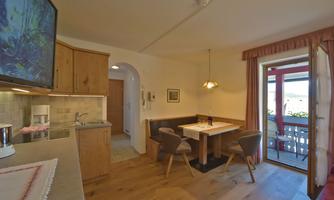 A cozy holiday apartment with a modern kitchen and a dining area. Through the large door, one enters a balcony with a view outside.