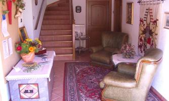 A cozy entrance area with a staircase in the background. Two comfortable armchairs on a colorful carpet and a table with a flower arrangement.