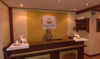 A reception desk in the Kaiser villa with a friendly employee. A welcome message and decorative elements create an inviting atmosphere.