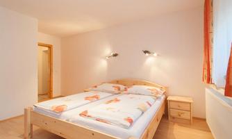A simple bedroom with a double bed and two nightstands. The walls are light-colored and the room is well-lit.