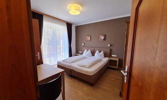 A cozy hotel room with two beds and a table. The windows provide plenty of daylight and a pleasant atmosphere.