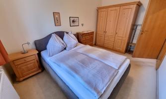 A cozy bedroom with a double bed and wooden furniture. The room has a warm, inviting character.