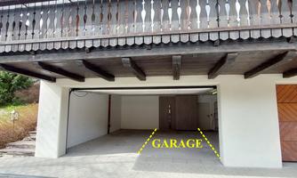 A garage with an open door and plenty of space. The area is clean and well-lit.